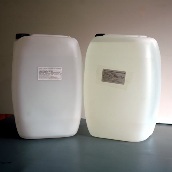 Due grosse taniche di plastica bianca con idrolato biologico certificato HACCP su un piano grigio e sfondo bianco-bruno con etichetta carta descrittiva del prodotto