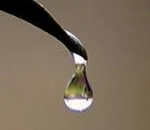 Effetto lente creato da una goccia di acqua trasparente in caduta da una foglia verde al mattino