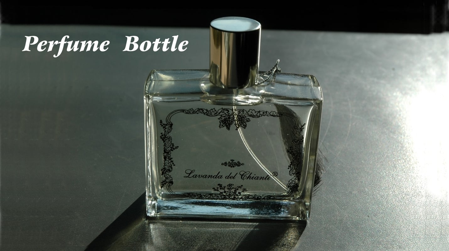 Transparent glass bottle with gold cap and silver plume on a shaded gray surface, black artistic label by the Sienese painter Vittorio Zani; white writing: perfume bottle
