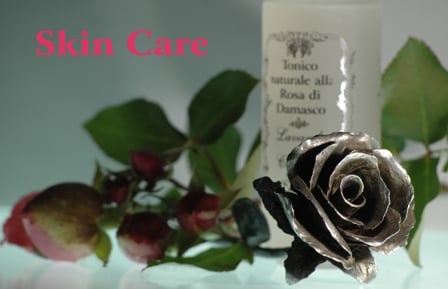 Lead-colored iron rose on a background of rosebuds and green petals with a glass bottle of tonic liquid