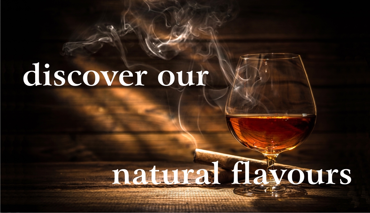 Bicchiere di Cognac mezzo pieno e 2 sigari appoggiati su tavola di legno e sfondo di talvole di legno grezzo, nuvola di fumo di sigaro e scritta: scopri i nostri aromi naturali